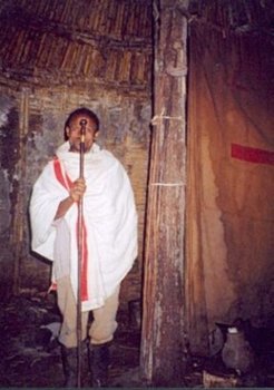 A spirit medium in Dawro, standing next to the central post of his ritual house, holding a spiritual stick he inherited from his father who was genealogically an Oromo but politically identified as an Amhara.