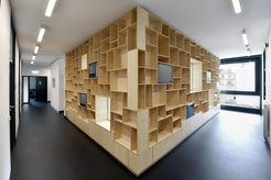 The warm colours of the birch plywood shelves contrast with the slate grey and white of the building’s interior.