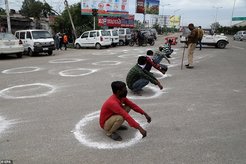 Men caught violating rules about public gatherings in India are forced to crouch inside chalk circles drawn on the ground to show them what mandatory minimum distances looks like amid the country's lockdown.